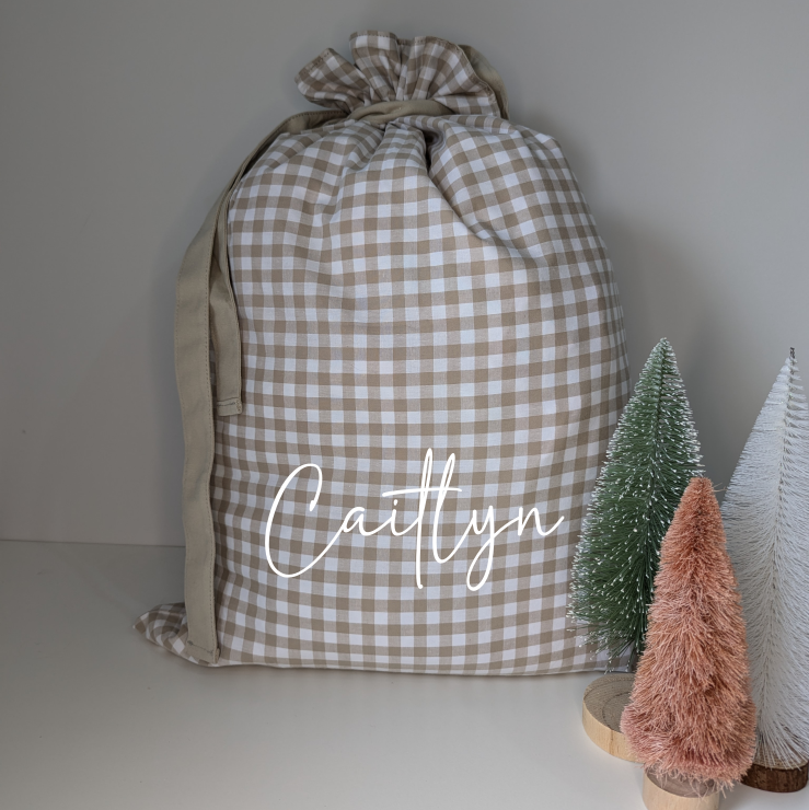 Gingham personalised Santa sack for Christmas. Custom name decal Santa sack. White and beige. Festive gifts. Neutral Christmas theme.