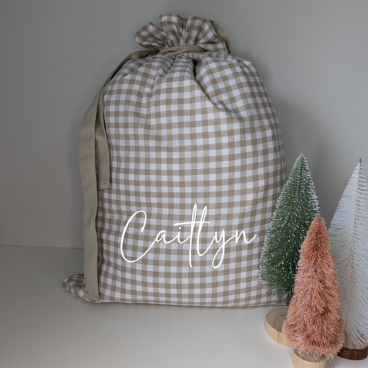 Gingham personalised Santa sack for Christmas. Custom name decal Santa sack. White and beige. Festive gifts. Neutral Christmas theme.